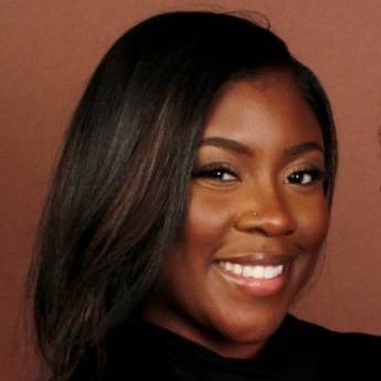 Headshot of Rakiah Brown.  A smiling Black woman with a black top and brown background.