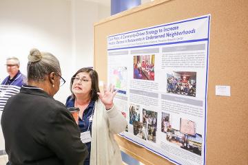 a woman gives a poster presentation 